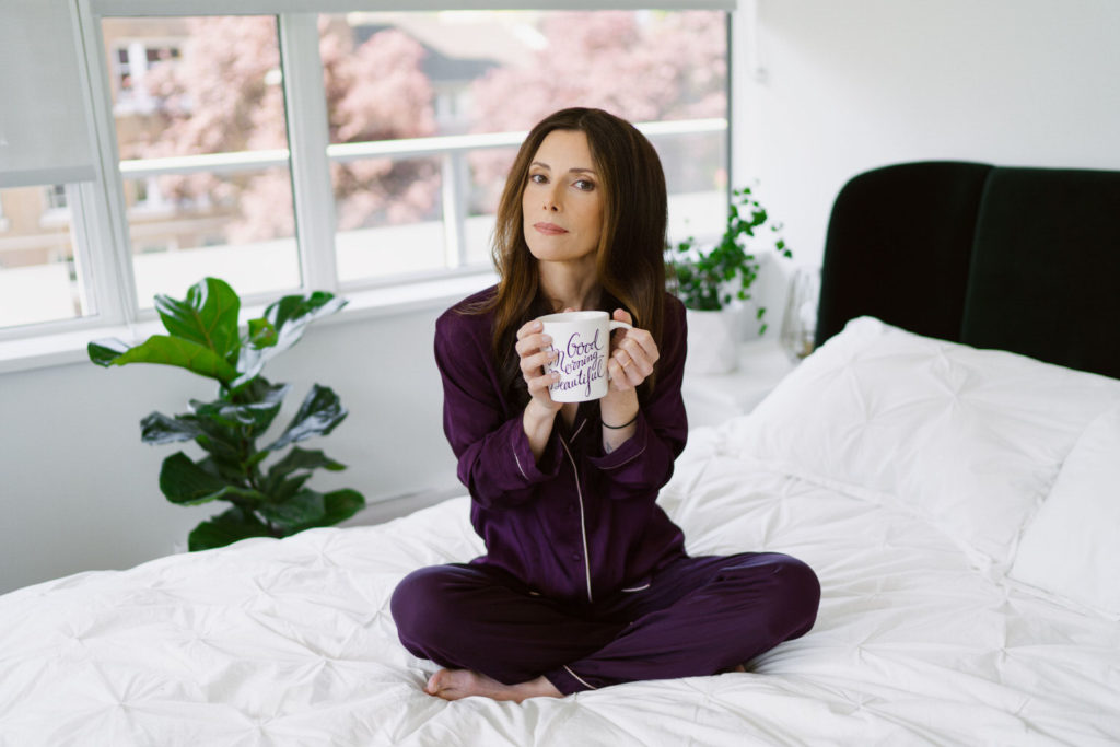 Girl in Pyjamas holder coffee mug on bed